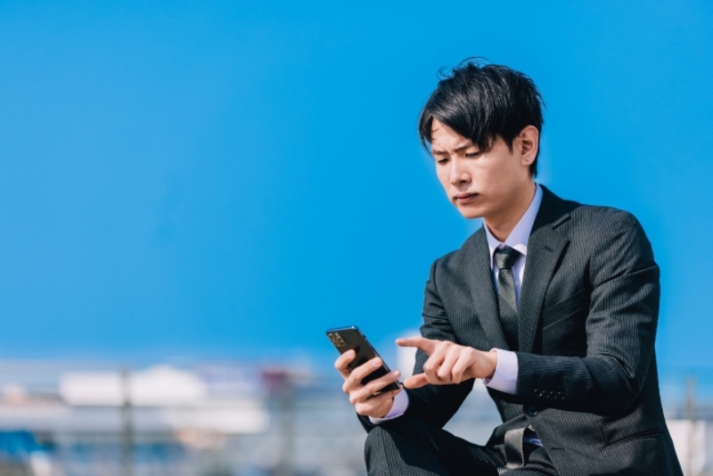 屋外でスマホを使う日本人男性ビジネスマンのイメージ